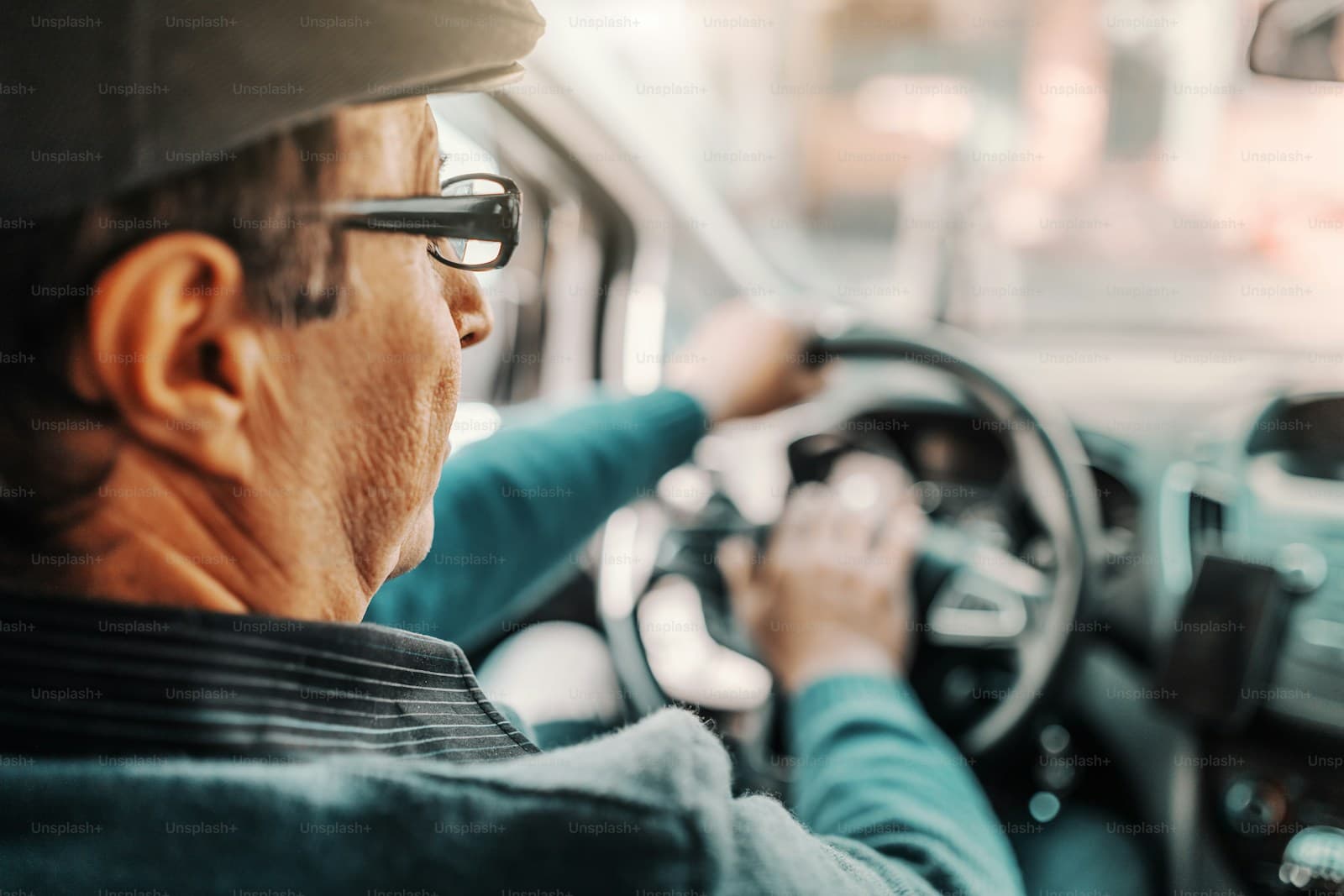 Middle-aged man in glasses gripping the wheel with both hands while driving