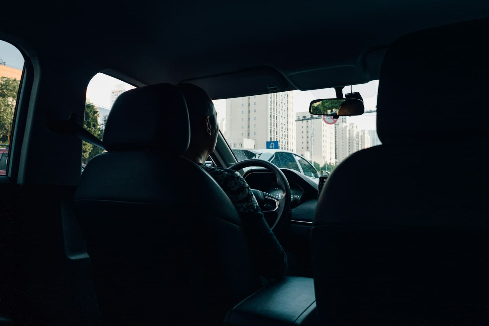 View from the back seat of a driver navigating a street lined with tall buildings