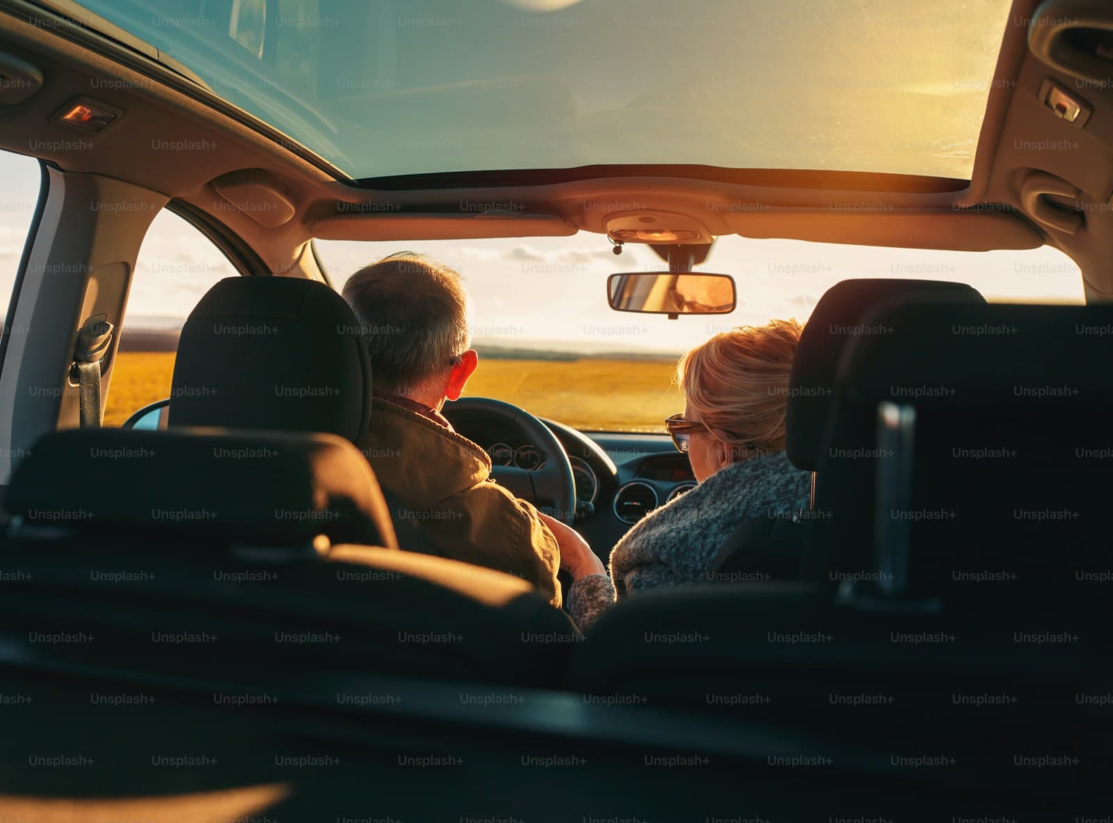 Two people driving through open farmland in warm golden-hour light